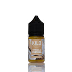 A 30ml bottle of Kilo Vanilla Almond Custard e-liquid, featuring a black childproof cap and a tan label with vanilla and almond illustrations, set against a plain white background with a soft reflection below.